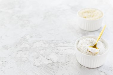 Pirinç unu ve pirinç gri bir masada beyaz kaselerde inliyor. Glütensiz, sağlıklı beslenme konsepti. Yatay yönelim, boşluğu kopyala.