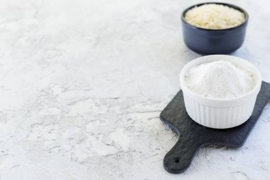 Siyah bir tahtanın üzerinde beyaz bir kasede pirinç unu. Sağlıklı gıda konsepti. Yatay yönelim, boşluğu kopyala.