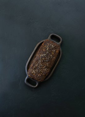 Siyah bir masada ev yapımı keten ekmeği. Dikey oryantasyon, üst görünüm. Sağlıklı yemek, glütensiz, şekersiz, laktozsuz.