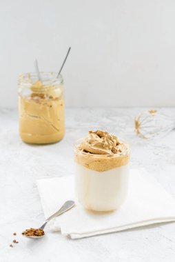 Kavanozlu çırpılmış dalgona kahvesi ve hafif bir masada çırpılmış çırpma..