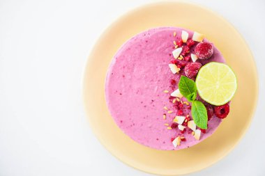 Beyaz bir masada ahududu ve limonlu kaju keki. Üst görünüm, boşluğu kopyala. Çiğ tatlı, şekersiz, glütensiz, laktozsuz..