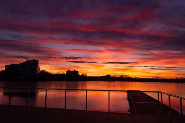Gölün üzerindeki görkemli günbatımı. Renkli doymuş bulutlar suya yansıyor. Dramatik sahne. Güzel manzara. Doğadaki renk. Dünyadaki güzellik.