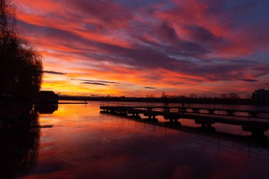 Gölün üzerindeki görkemli günbatımı. Renkli doymuş bulutlar suya yansıyor. Dramatik sahne. Güzel manzara. Doğadaki renk. Dünyadaki güzellik.