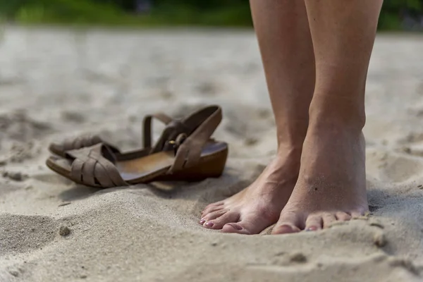 female feet on sand at beach in summer in sunny weather