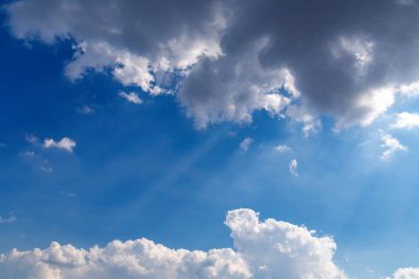 Bulutlar mavi gökyüzünde güneş ışınlarıyla
