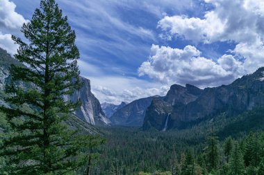 Yosemite Ulusal Parkı gözlem güvertesinden dağlara ve şelaleye güneşli havada bulutlu mavi gökyüzüne