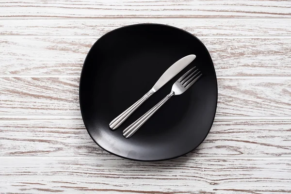 Plaque vide couteau fourchette argenterie blanc fond de table en bois — Photo