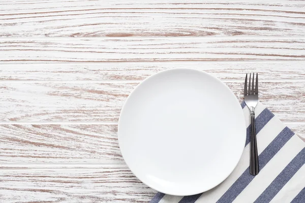 Plato vacío servilleta tenedor plata fondo de mesa de madera blanca —  Fotos de Stock