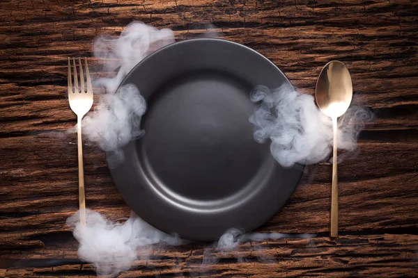 Cucchiaio forchetta piatto vuoto nero su sfondo tavolo di legno — Foto Stock