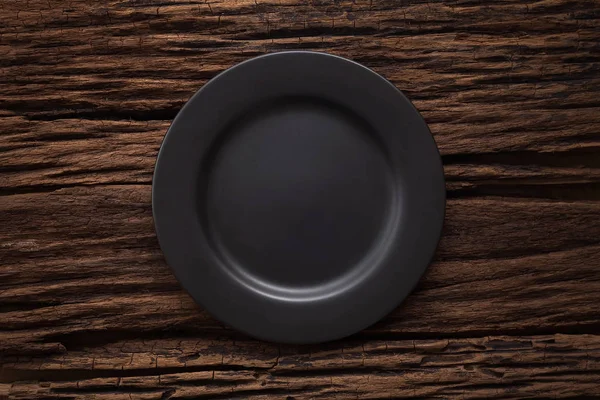 Plato vacío negro sobre fondo de mesa de madera — Foto de Stock