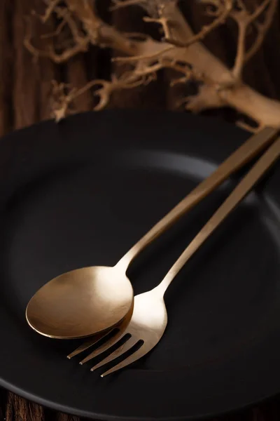 Cucchiaio forchetta piatto vuoto nero su sfondo tavolo di legno — Foto Stock