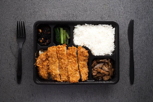 Japanese food tonkatsu rice and vegetable take away on table background