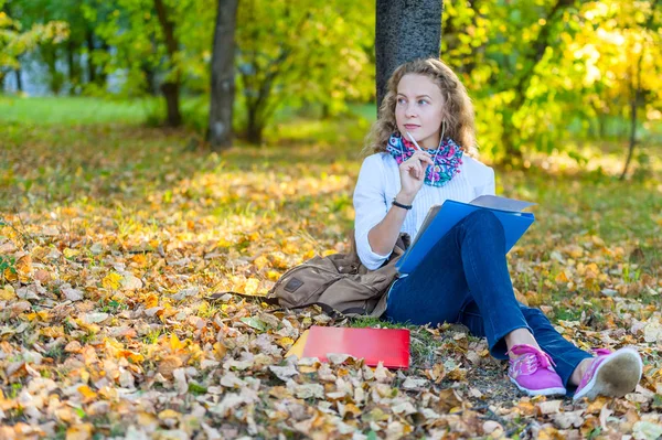 Student zadumany dziewczyna siedzi i pisze w parku jesień — Zdjęcie stockowe