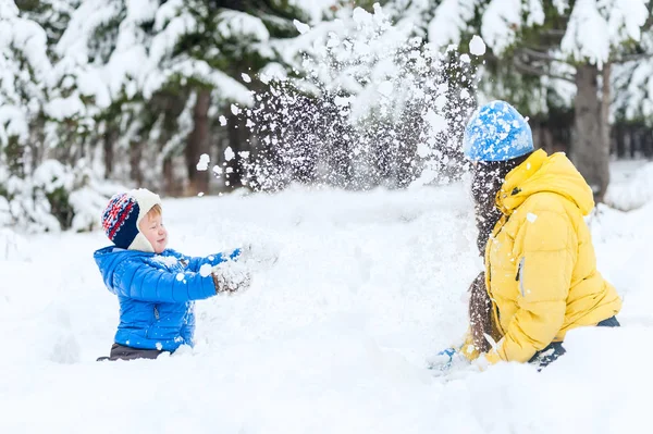 Мать и ребенок играют в зимнем парке. Завалило снегом — стоковое фото
