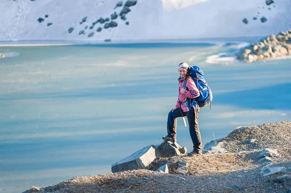 Chica joven con mochila de pie en la orilla de un lago congelado — Foto de Stock