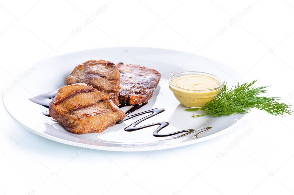 Grilled pork steak with sauce and greens on a white background