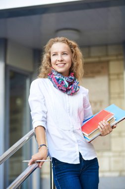 Merdiven üstünde duran ve klasörleri tutmak gülümseyen kız öğrenci