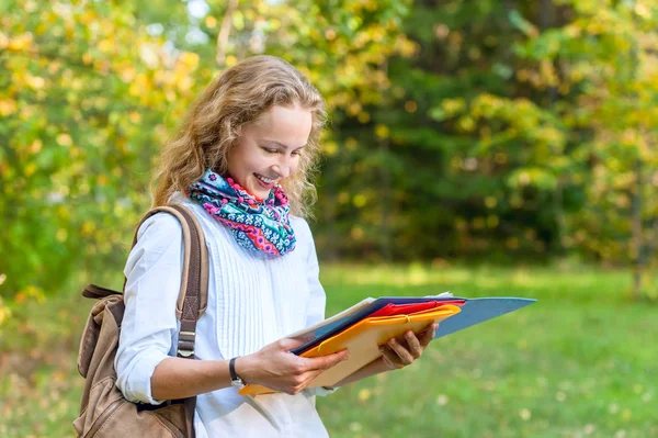 Étudiante souriante lisant un cahier dans le parc d'automne — Photo