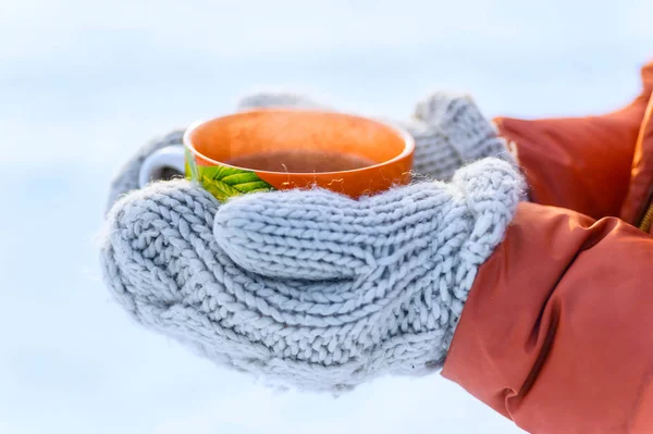 Vrouw handen in gebreide wanten holding mok hete thee in de winter park — Stockfoto
