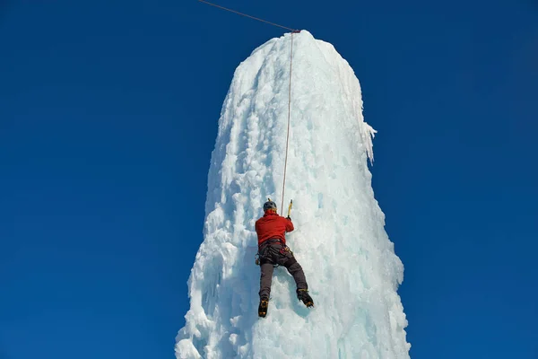 Homme alpiniste avec des outils de glace hache escalade un grand mur de glace. Portrait de sport extérieur — Photo