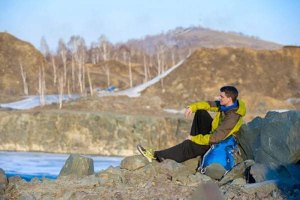 Un jeune homme avec un sac à dos assis sur le bord du lac d'automne — Photo