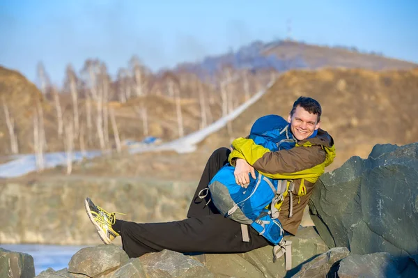 Jeune voyageur assis sur les rochers avec un sac à dos et souriant — Photo