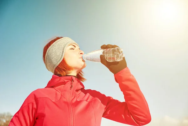 Jeune femme boit de l'eau de bouteille après le jogging dans la ville d'hiver — Photo