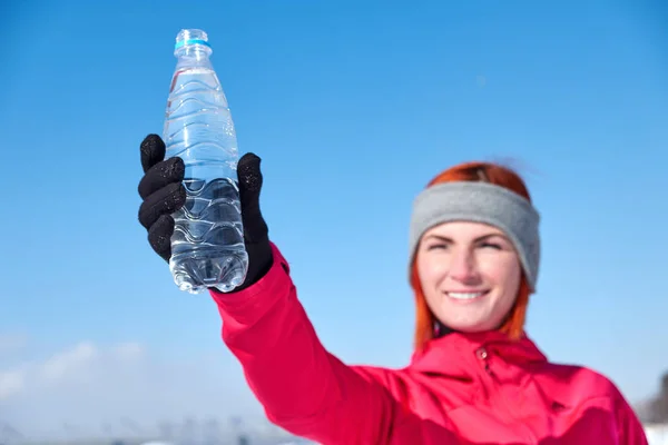 Jeune femme avec bouteille d'eau après le jogging dans le parc d'hiver — Photo