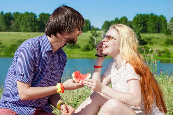 Happy couple on picnic eating watermelon,having fun together. outdoor portrait on lake — Stock Photo, Image