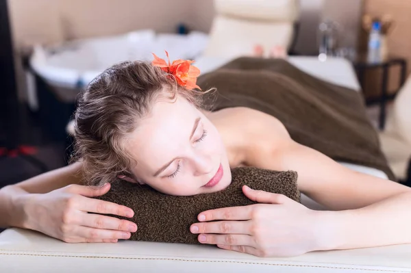 Mujer en una mesa de masaje relajante en el salón de spa. retrato de belleza —  Fotos de Stock