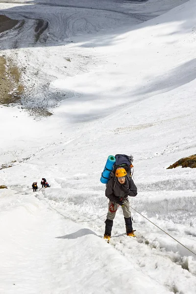 L'alpiniste atteint le sommet d'une montagne enneigée — Photo