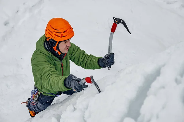 Homme alpiniste avec piolet à outils en casque orange escaladant une lar — Photo