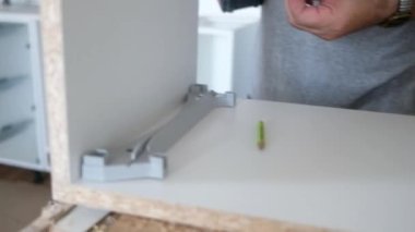 Marangoz evde mobilya yapıyor, matkapla çalışıyor.