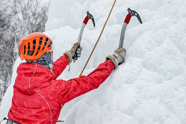 Alpinist γυναίκα με εργαλεία πάγου τσεκούρι σε πορτοκαλί κράνος αναρρίχηση a la — Φωτογραφία Αρχείου