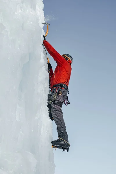 Homme alpiniste avec des outils de glace hache escalade un grand mur de glace. Ou — Photo