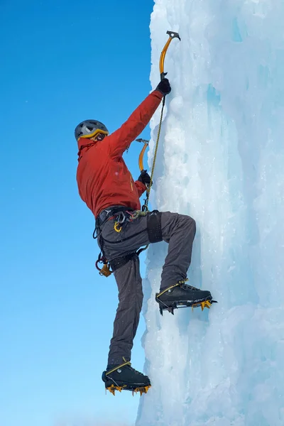 Homme alpiniste avec des outils de glace hache escalade un grand mur de glace. Portrait de sport extérieur. — Photo
