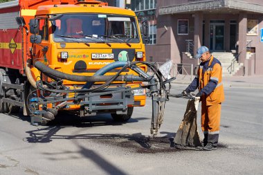 Novosibirsk, Rusya - 2 Eylül 2019: Yol inşaatı, endüstri ve takım çalışması yapan işçiler. Kürekli asfalt yolda çalışan insanlar.