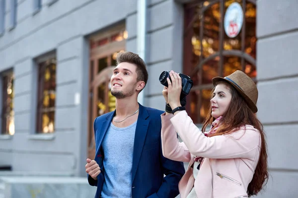 Amor feliz pareja de turistas tomando fotos en excursión o tour por la ciudad. Fotos sobre el fondo de la arquitectura urbana —  Fotos de Stock