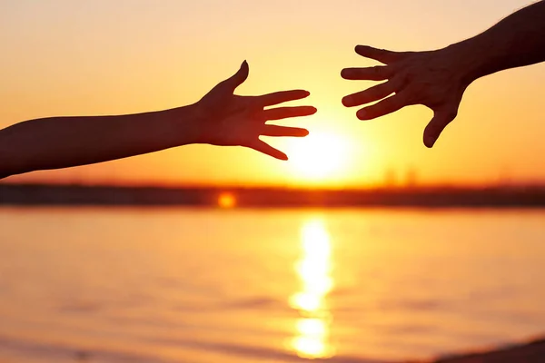 Giving a helping hand. Silhouette Two hands, man and woman, reaching towards each other at sky sunset — Stock Photo, Image