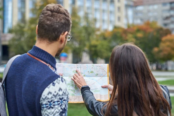 Casal de jovens turistas lendo um mapa e procurando local na cidade — Fotografia de Stock