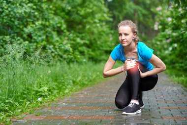 Kadın atlet, dizine acı içinde dokunuyor, kadın sporcu yaz parkında koşuyor. Sağlıklı yaşam tarzı ve spor anlayışı