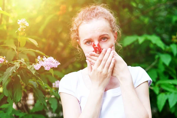 Alergia. Kobieta ścisnęła swój nos ręką, żeby nie kichnąć z pyłku kwiatów. Kobieta chroniąca nos przed alergenami za pomocą szpilki do ubrań — Zdjęcie stockowe
