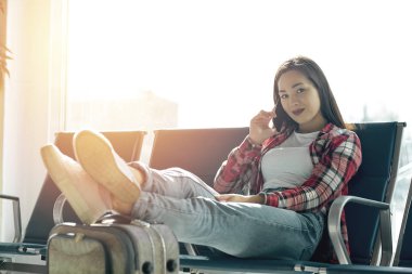 Sıradan bir genç kızın el bagajıyla oturduğu hava yolculuğu konsepti. Havaalanındaki kadın terminalde bekliyor..