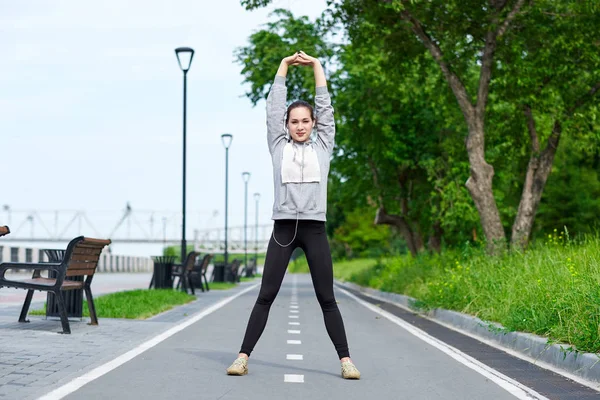 Mujer joven fitness estirándose después de correr. retrato deportivo al aire libre — Foto de Stock