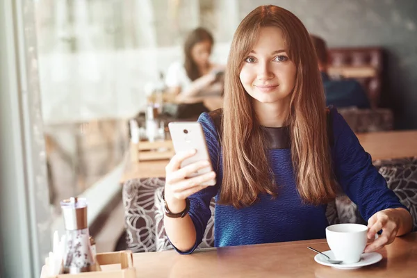 Joven mujer de negocios usando su teléfono inteligente y sonriendo en la cafetería — Foto de Stock