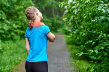 Eğitim sırasında boyun ağrısı. Spor sakatlığı olan koşucu bir bayan sporcu yaz egzersizinden sonra sırt kaslarını ovuyor ve dokunuyor..