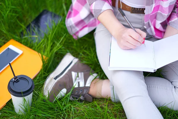 Adolescente étudiante écrit dans un cahier dans le parc. Préparation aux examens au collège ou à l'université — Photo