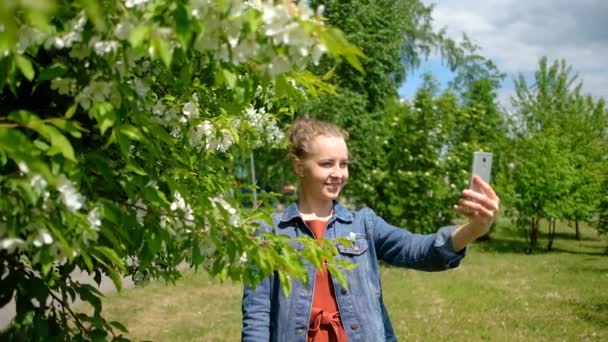 Mooie vrouw maken selfie in groene lente bloeiende park — Stockvideo