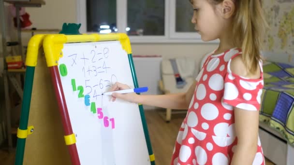 Девочка, использующая магнитную доску для изучения букв и цифр дома — стоковое видео