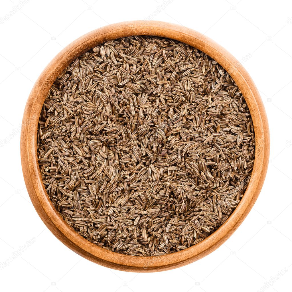 Caraway seeds in a wooden bowl over white